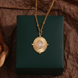 Detailed macro view of 18K gold-plated oval pendant with white natural stone on green box
