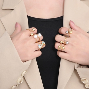 Detail of gold and silver sphere rings with white pearls and rhinestones on hands