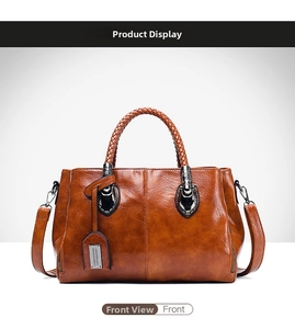 Detail view of brown wax leather Boston bag featuring woven handles and metal tags