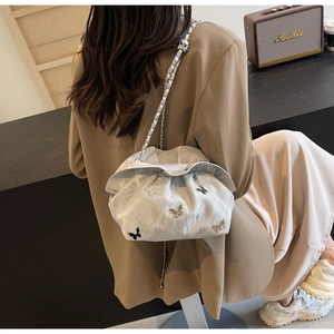Close-up of silver pleated bucket bag with metallic butterfly and chain strap