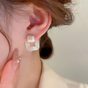 Detailed close-up of matte silver square geometric earrings with brushed U-shaped pendant