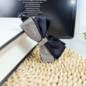 Dettaglio di un fermaglio vintage a fiocco nero con strass argentati brillanti e chic