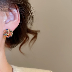 Close-up of gold-plated square stud earrings with colorful zircon mosaic on a model ear