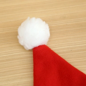 Detailed view of red Christmas hat top with a soft white plush pom-pom on wood background
