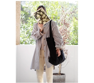 Lifestyle view of a large black canvas shoulder bag styled with a grey casual shirt