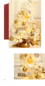 Macro shot of flocked mini Christmas tree with gold ornaments and warm LED lights
