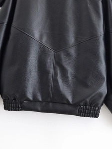 Détail d'une veste en cuir noir grainé montrant les coutures du dos et l'ourlet