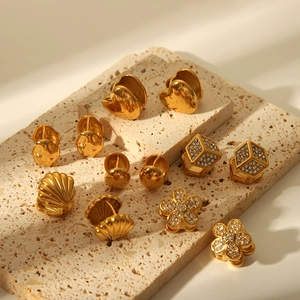 Détail de plusieurs boucles d'oreilles en acier inoxydable doré sur pierre beige