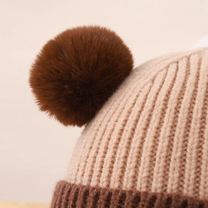 Detailansicht der Strickstruktur und des großen braunen Bommels der Kindermütze