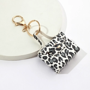 Mini leopard print bag keychain with gold metal clasp on white display stand
