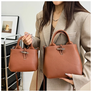 Detail shot showing the leather texture and bamboo clasp of the brown bucket bag