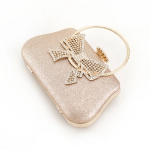 Detailed view of the sparkling gold evening bag with a crystal rhinestone bow and metal handle