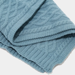 Makro-Detail des himmelblauen Zopfstrickmusters mit dicken Rippbündchen und warmer Textur