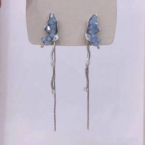Detail of silver butterfly tassel earrings featuring light blue crystals and wavy chains