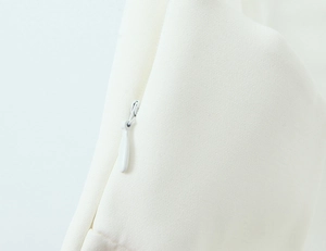 Close-up of white elastic mini dress featuring a concealed side zipper and woven texture