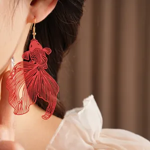 Élégantes boucles d'oreilles carpe koï ajourées avec laqué rouge sur le modèle