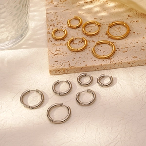 Polished stainless steel hoop earrings in gold and silver, variety of sizes on stone slab