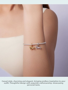 Close-up of gold and silver dachshund charms with zircons on a silver mesh bracelet