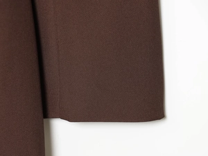 Gros plan détaillé sur le tissu marron foncé à texture fine de cette robe blazer