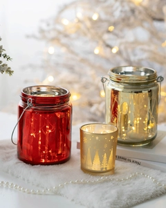 Close-up of glass Christmas candle holders with gold reindeer and snowflake patterns