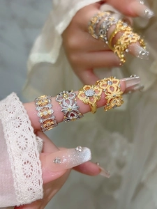 Détail de bagues fleurs rhombiques plaquées or avec zircons portées sur la main d'un mannequin