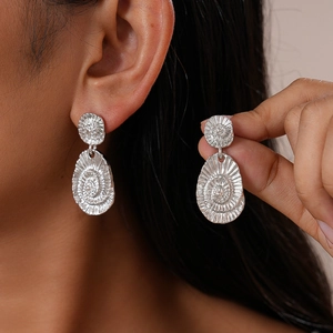 Boucles d'oreilles ovales géométriques en métal argenté avec texture radiale portées et tenues