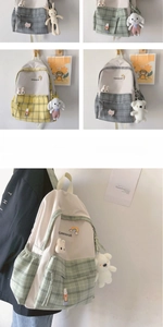 Detail of canvas school backpack featuring plaid patterns, brand logo, and cute plush charms
