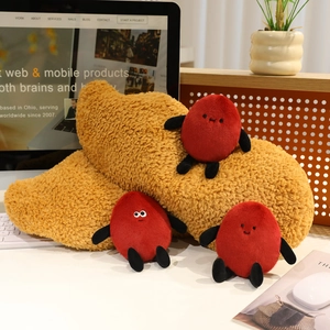 Macro detail of plush peanut pillow and small cartoon dolls on office desk setting