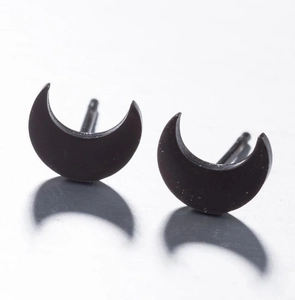 Macro shot of minimalist matte black crescent moon stud earrings on a light grey surface