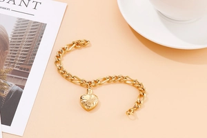 Close-up of golden stainless steel chain bracelet featuring a textured heart pendant