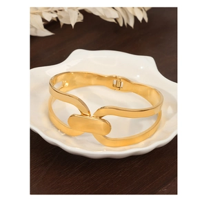 Detail of a double-layered gold geometric bracelet resting on a white ceramic plate