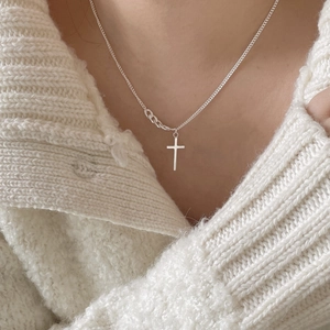 Close-up of 925 sterling silver cross pendant necklace on white knitted sweater background