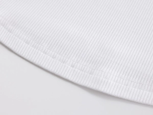 Macro detail of white ribbed knit fabric showing high-quality double-stitch hem finishing