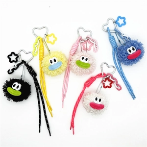 Flat lay of colorful monster plush keychains with heart hooks and woven straps