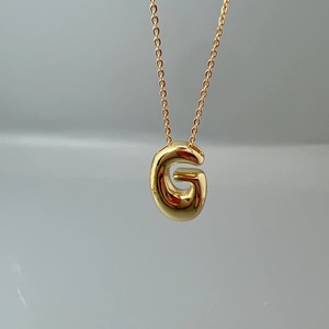 Macro shot of polished gold letter G pendant on a fine O-chain necklace