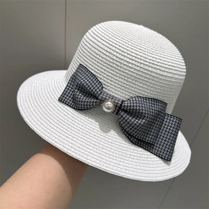 Close-up of white woven straw hat with checkered bow and large pearl detail