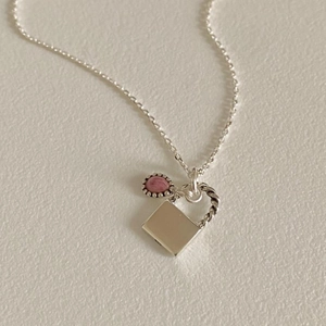 Detail of 925 sterling silver necklace featuring a pink stone and engraved silver plaque