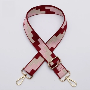 Close-up of adjustable woven bag strap with geometric pattern and gold metal hooks