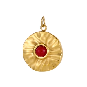 Detail of vintage gold stainless steel pendant with hammered texture and red stone