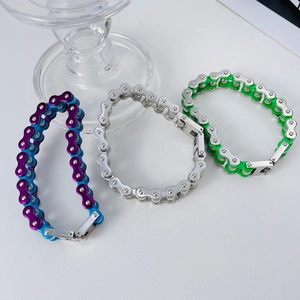 Three men's stainless steel bicycle chain bracelets in purple, silver, and green finishes