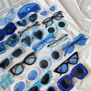 Flat lay of colorful cat-eye and heart-shaped sunglasses on white fabric