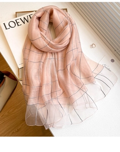 Detail of pink silk wool scarf with black pinstripe pattern on a minimalist desk