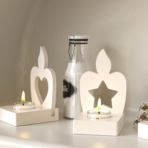 Close-up of minimalist cream white wooden candle holders with hollow heart and star shapes