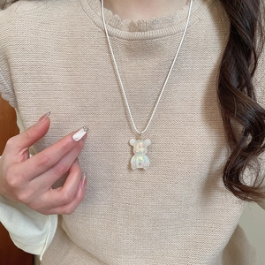 Close-up of a white iridescent resin bear pendant necklace on a model's neck
