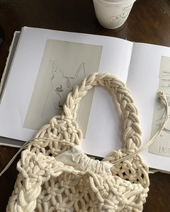 Detailed close-up of beige hand-woven tote bag with thick cotton rope texture on wooden desk