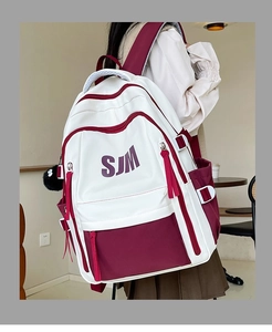 Detail showing white and burgundy vintage backpack with long zippers and pompom on back