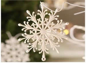 Macro detail of white glitter snowflake ornament with hanging hole on a blurred background