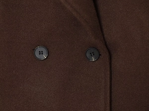 Detail of dark brown wool jacket featuring high-quality fabric texture and black buttons