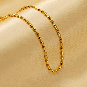 Polished 18K gold plated oval bead chain necklace displayed on soft champagne silk fabric