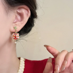 Detail of red enamel lion dance earrings with gold star studs and pearl pendants